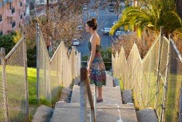 Woman standing on a bridge with cityscape background, exploring new destinations. 