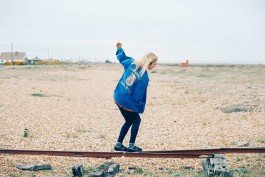 Girl balancing on a railway track at the beach. 