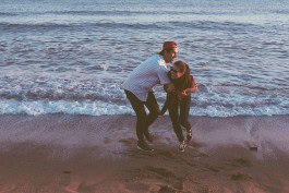 Happy couple enjoying a playful moment on the beach at sunset. 