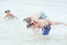 Family enjoying playful beach time and swimming in the ocean. 