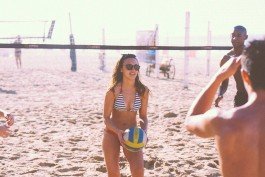 Women playing beach volleyball on sandy shore during sunny day. 