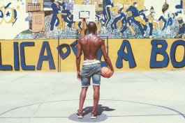 Young man standing with a basketball, ready to play on an urban court. 