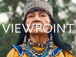 Indigenous woman wearing traditional beaded headdress and jewelry outdoors. 