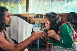 Robin Mellor - Indigenous healing ceremony featuring a shaman offering a sacred drink to a woman in a traditional s. 