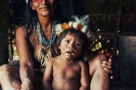 Indigenous woman and child from a tribal community, showcasing traditional face paint and attire in. 