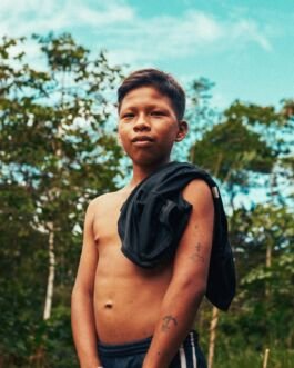 Boy with backpack outdoors in nature, looking confidently at the camera. 
