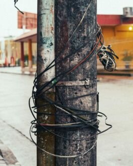 Wires wrapped around a weathered utility pole in an urban environment. 