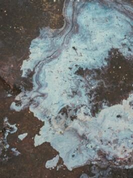 Abstract blue and black marbled artwork with swirling patterns and textured surface. 