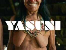 Topless woman wearing colorful beaded necklaces with a large white 'YASUNI' logo across the chest. 