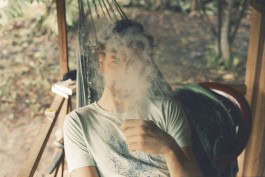 Robin Mellor smoking outdoors in a cozy, rustic setting. 