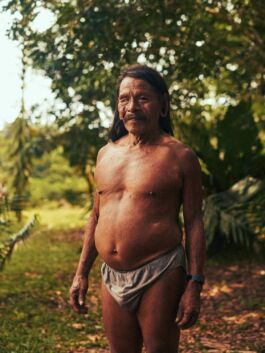 Elder man with long hair standing outdoors, embracing nature and cultural identity. 