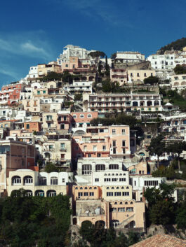 Colorful hillside town with white and pastel houses stacked on a steep slope under a clear blue sky. 